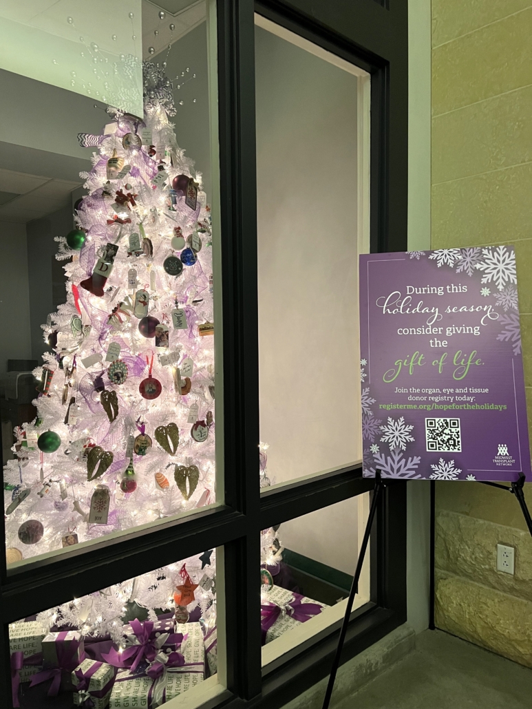 A holiday tree with a sign next to it