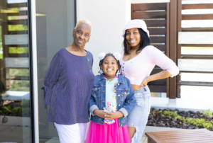 Portrait photograph of Maxine McMullen standing outside with two of her younger female family members.