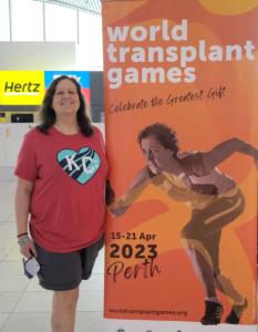 a person standing next to a poster for world transplant games