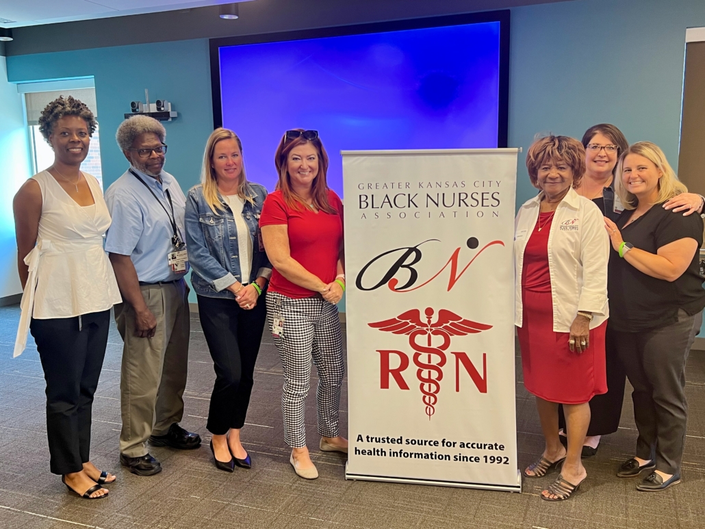 people next to a poster for Greater Kansas City Black Nurses Association