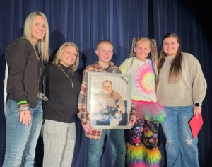 Five people are center stage during intermission at a school musical, posing for a photo.