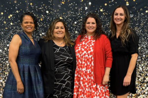 Four ladies posing for a picture in front of a star-themed background.