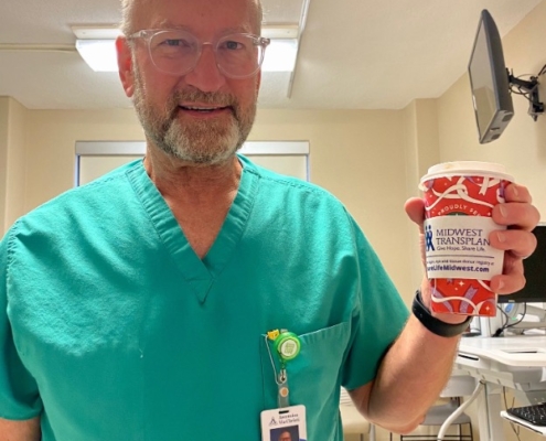 Photo of a male doctor holding a coffee cup with the MTN coffee sleeve.