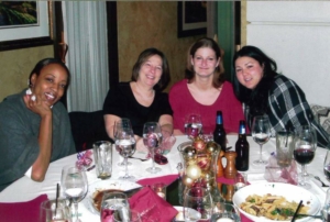 A group of people posing for a photo around a table with food and drinks