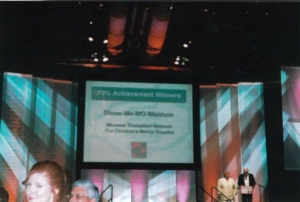 A screen at an event that says 75% Achievement Winners Show-Me-Mo-Mentum