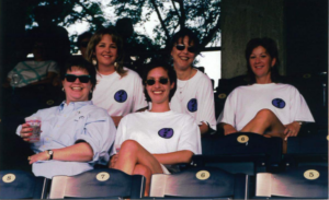 five people sitting on bleachers wearing white shirts