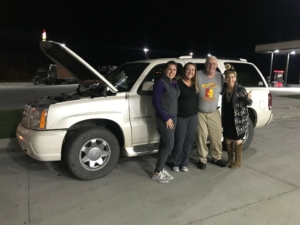 people posing in front of a car with the hood open