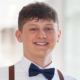 A headshot of donor hero Drew Hedrick in white shirt, black bow tie and suspenders.