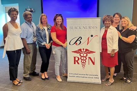 people next to a poster for Greater Kansas City Black Nurses Association