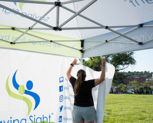 person hanging a banner in a tent