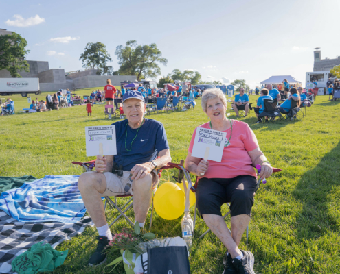 two people sitting in chairs and holding signs