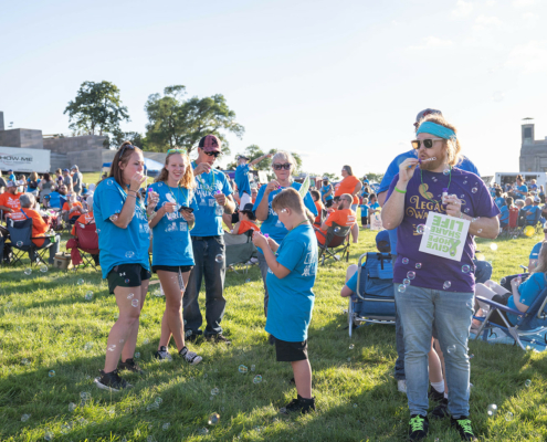 people standing on a field and blowing bubbles