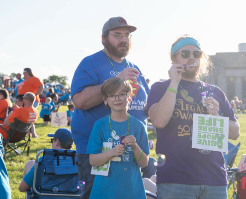 three people standing on a field and blowing bubbles