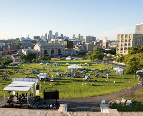 bird's eye view of a grass field with tents and a city in the background