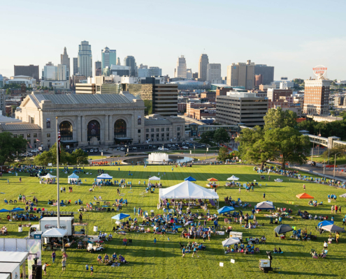 bird's eye view of a grass field with tents and a city in the background