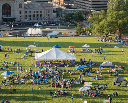 bird's eye view of a grass field with tents and a city in the background