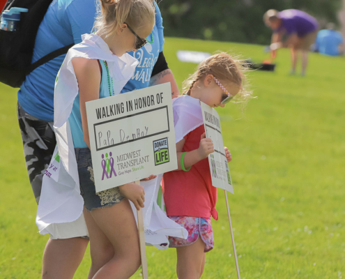 People walking on a grass field holding signs