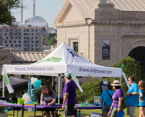 People walking in front of a tent with a city in the background