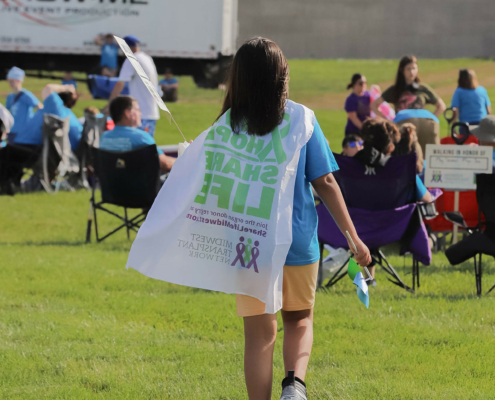 a person walking on a grass field wearing a cape