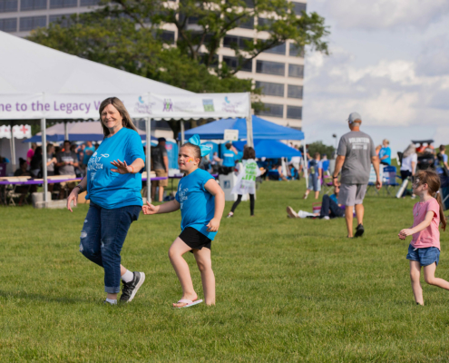 People dancing on a grass field with a tent in the background