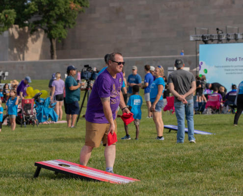 People playing cornhole outside on a grass field