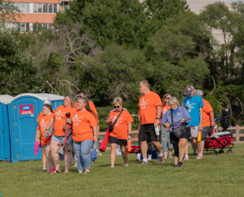 People wearing orange and blue shirts walking across a field