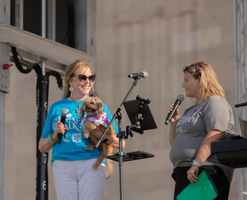 a person on stage holding a microphone and a dog next to another person holding a microphone