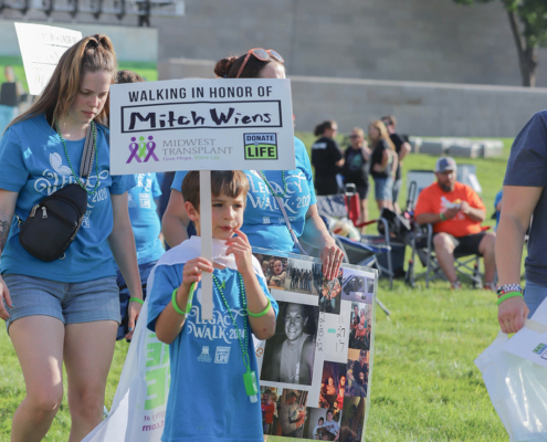 a child holding a sign that says walking in honor of Mitch Wiens