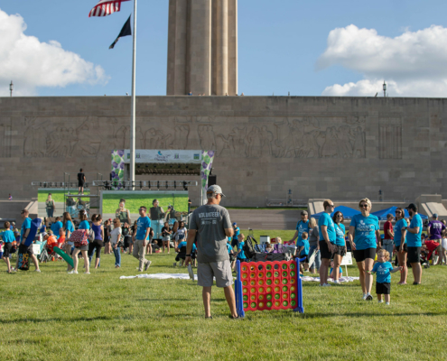 a person standing next to an outdoor connect four with a stage and a building in the background