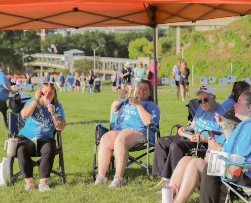 people sitting in chairs blowing bubbles under a tent