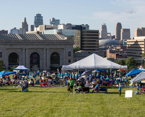 people at an outdoor event with a tent and a city in the background