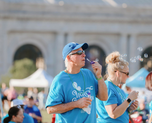 Two people standing and blowing bubbles at an outdoor event