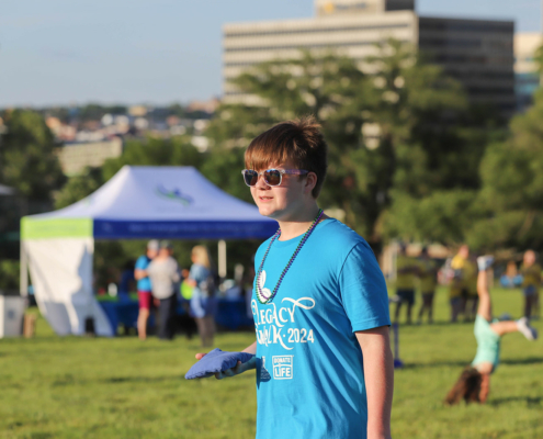 a person with a blue legacy walk shirt outside