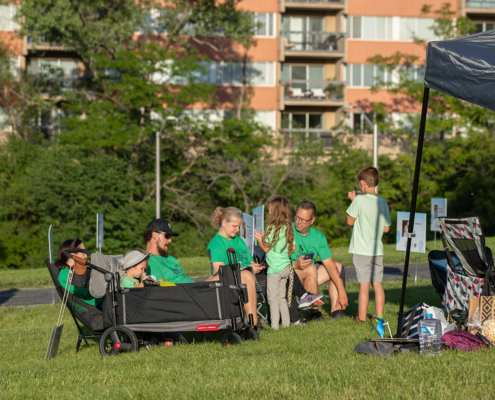 adults and children sitting next to a tent outdoors