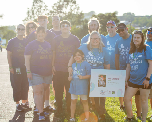 a group of people posing for a photo with a sign that says Jake Glasford Donor