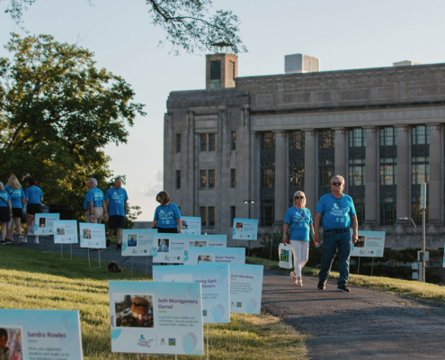 people walking along a path with posters of donors along the edge