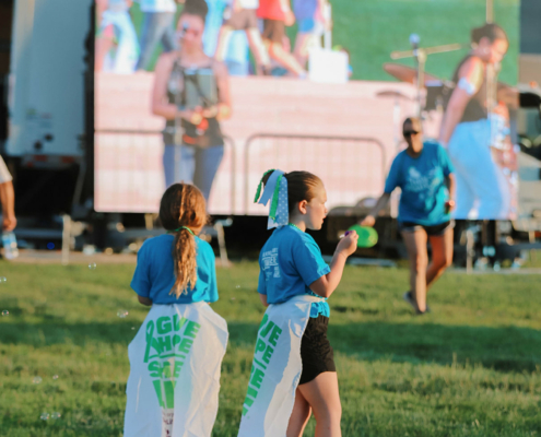 Children standing outdoors with a stage in the background