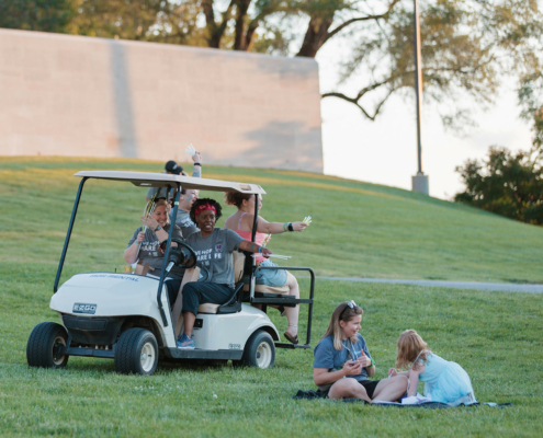 People giving out glow sticks from a golf cart