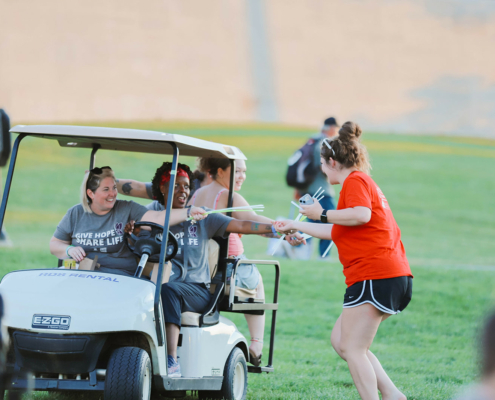 People giving out glow sticks from a golf cart