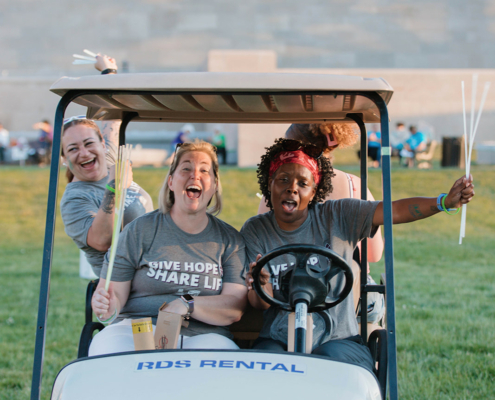 Three people smiling in a golf cart