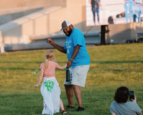 An adult and child dancing on grass