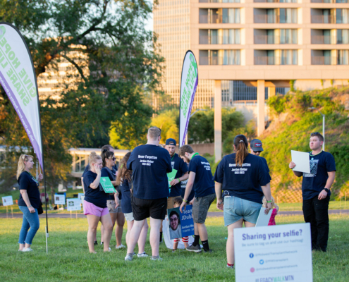 A group of people wearing matching navy blue shirts stand together at an outdoor event.