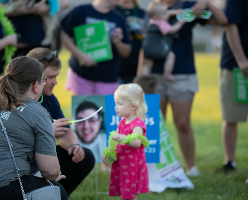 two adults giving a child a glow stick