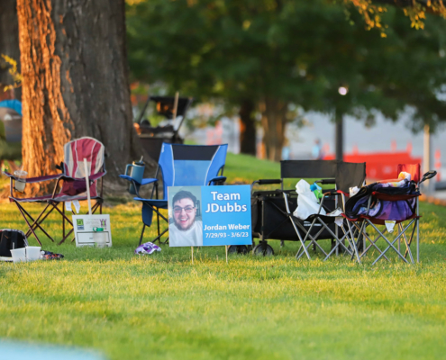 Chairs on a grass field with a poster for Team JDubbs in front