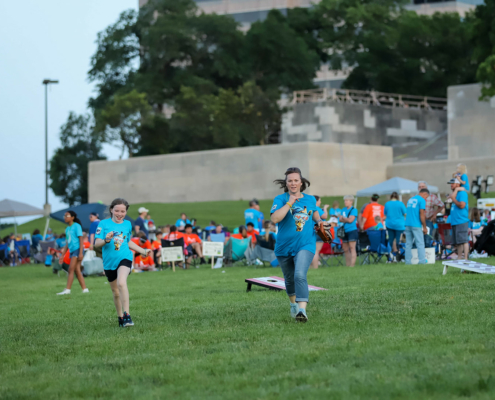 Kid and adult running on a grass field